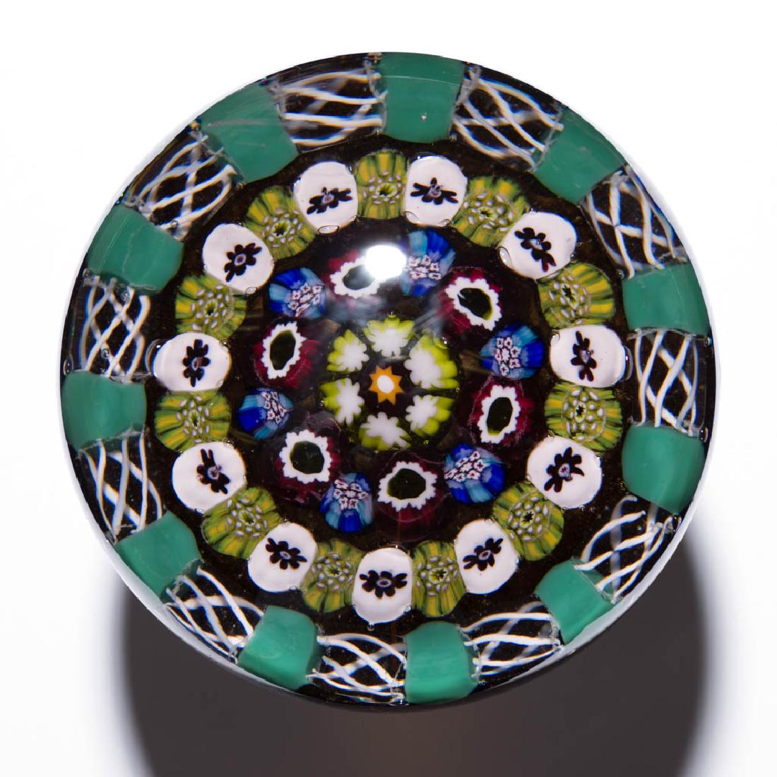 EARLY PAUL YSART STUDIO ART GLASS MILLEFIORI: EARLY PAUL YSART STUDIO ART GLASS MILLEFIORI PAPERWEIGHT, colorless with a grey tint, central orange star cane, encompassed by three rows of millefiori canes with many having a floral motif, outer row