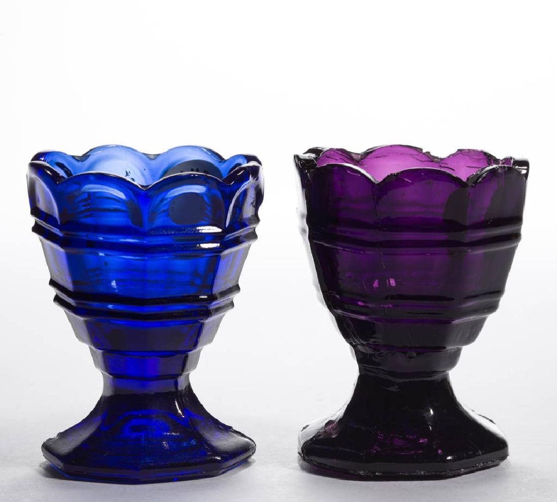 RINGED OCTAGONAL PRESSED OPEN SALTS / EGG CUPS, LOT OF: RINGED OCTAGONAL PRESSED OPEN SALTS / EGG CUPS, LOT OF TWO, deep amethyst and deep blue, each bowl with an eight-scallop rim, raised on a flared octagonal foot with rough pontil mark. Probably United