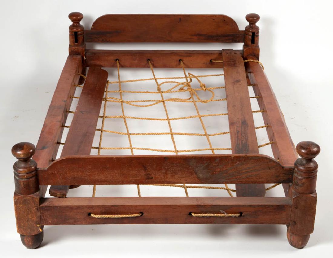 NEW ENGLAND PAINTED TRUNDLE ROPE BED: NEW ENGLAND PAINTED TRUNDLE ROPE BED, elaborate turning to the bed's posts. Retains an old, possibly original, red-washed surface. First half 19th century. 11" H, 38 1/2" W, 63 3/4" D.Very good condit