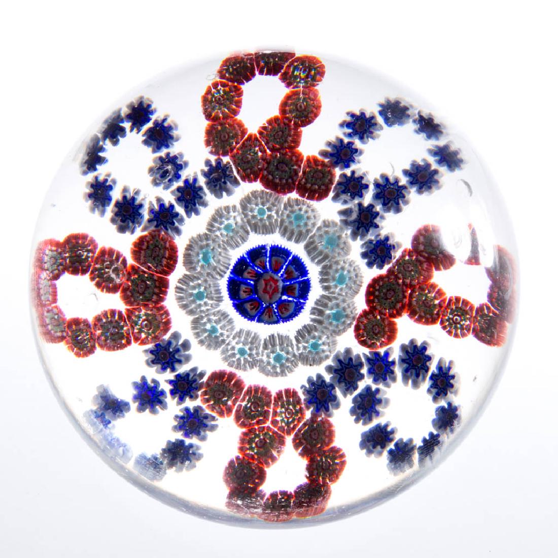 ANTIQUE BACCARAT MILLEFIORI GARLAND PAPERWEIGHT: ANTIQUE BACCARAT MILLEFIORI GARLAND PAPERWEIGHT, colorless, having central arrowhead cane, within ring of white and pale blue stardust canes, encompassed by loops of ruby, white, and blue millefiori c
