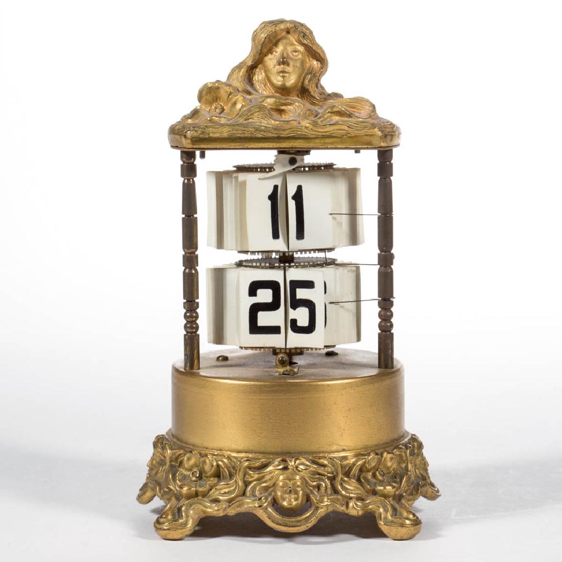 GILT-METAL PLATO DESK FLIP CLOCK: GILT-METAL PLATO DESK FLIP CLOCK, cylindrical case with ornamentation in the Art Nouveau style, movement marked "THE PLATO CLOCK" with various 1902 and 1903 patent dates. Early 20th century. 6" HOA.La