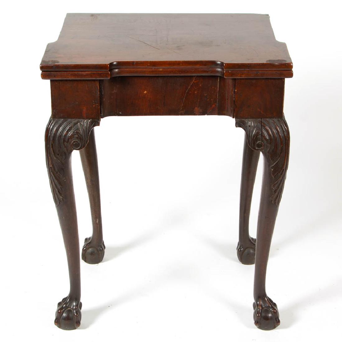 GEORGIAN CARVED MAGHOGANY FOLD-OVER GAME TABLE: GEORGIAN CARVED MAGHOGANY FOLD-OVER GAME TABLE in the manner of Thomas Chippendale, baized-lined, hinged top above a plain frieze, one drawer, raised on acanthus-carved cabriole legs terminated in bal