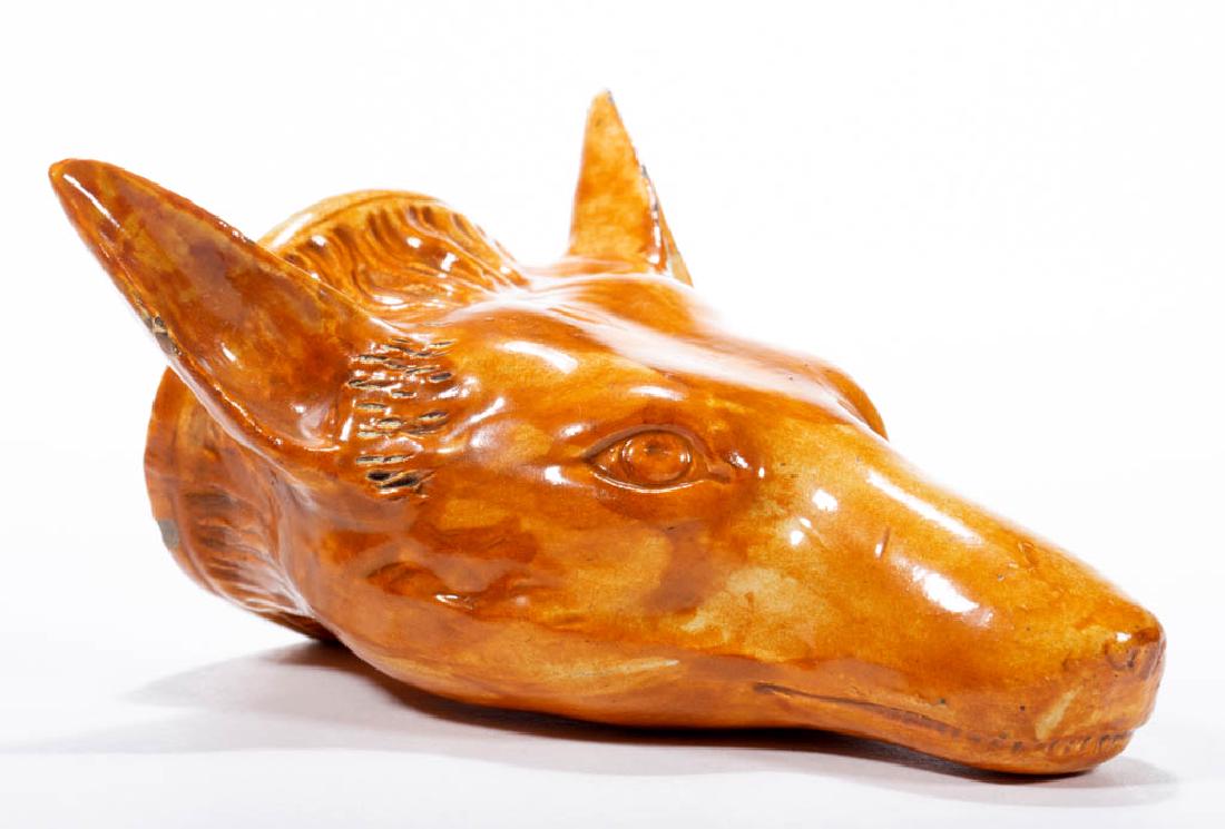 ENGLISH STAFFORDSHIRE PEARLWARE CERAMIC FOX STIRRUP CUP: ENGLISH STAFFORDSHIRE PEARLWARE CERAMIC FOX STIRRUP CUP orange glazed, with incised fur detail in front of ears. Circa 1790. 5" HOA. Some chips and flakes to ears, two spots of wear on chin, and one e