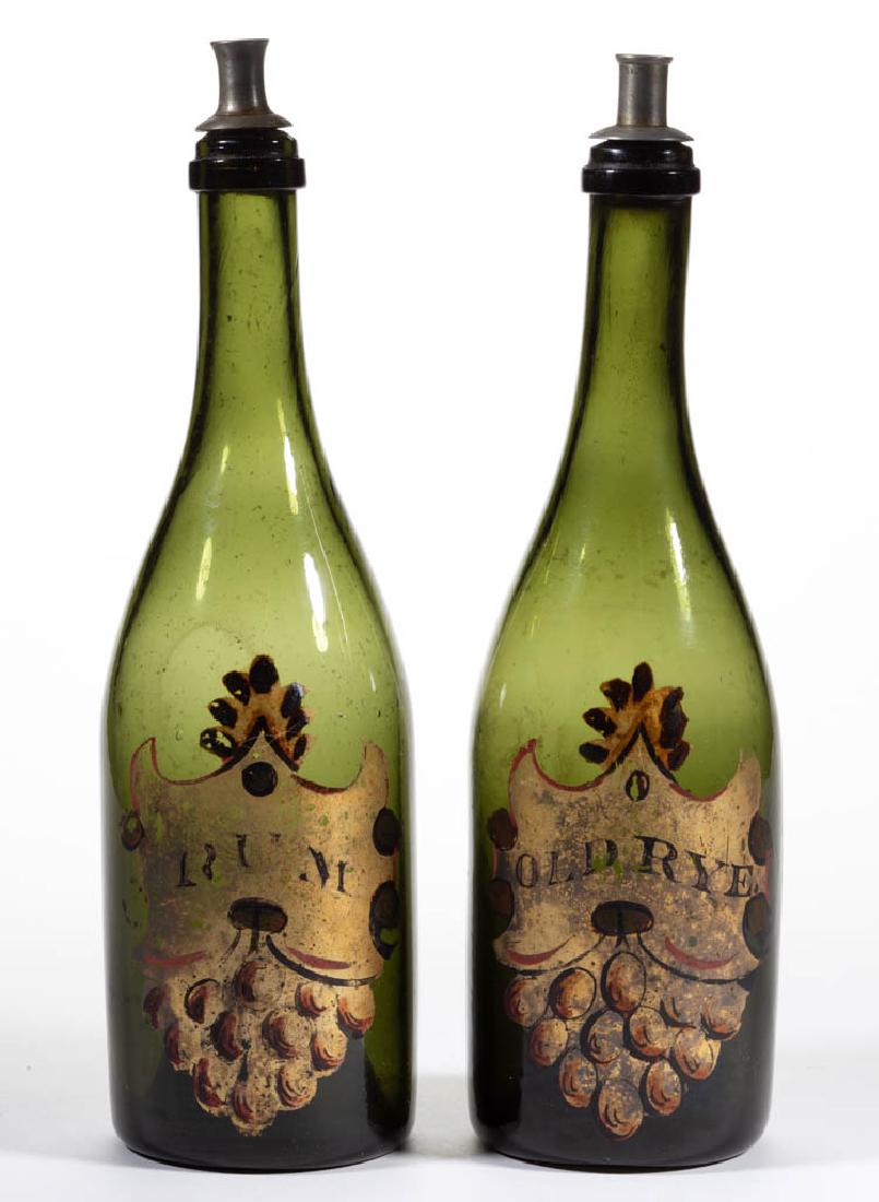 BLOWN AND DECORATED BOTTLES, LOT OF TWO: BLOWN AND DECORATED BOTTLES, LOT OF TWO, olive green, each tall cylindrical form with applied mouth rings, matching enamel-decoration with one stating "OLD RYE" and the other "RUM", each with a Britan