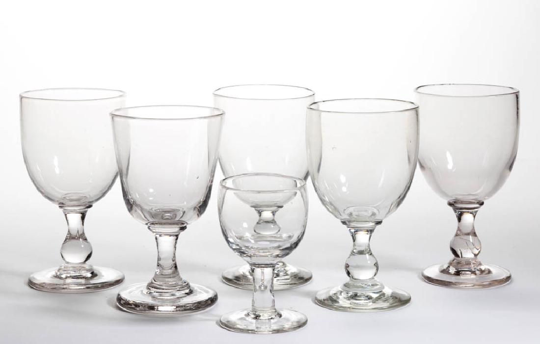 FREE-BLOWN GLASS DRINKING ARTICLES, LOT OF SIX: FREE-BLOWN GLASS DRINKING ARTICLES, LOT OF SIX, colorless, comprising five goblets and a wine, goblets with a polished pontil mark and wine with a rough pontil mark. Maker unverified. 19th century. 3 