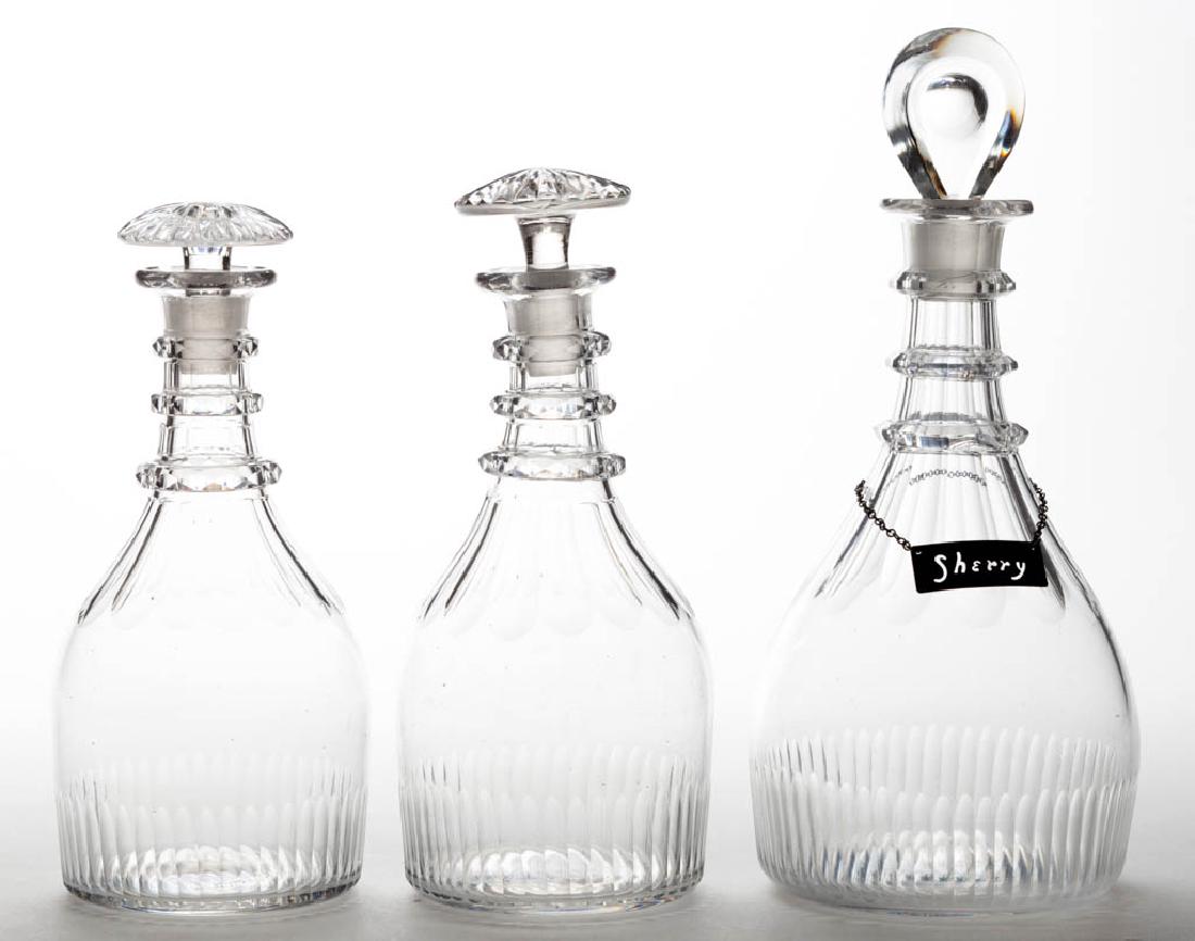 CUT-FLUTE GLASS DECANTERS, LOT OF THREE: CUT-FLUTE GLASS DECANTERS, LOT OF THREE, colorless lead glass, comprising two pint and a quart example with a "HANDMADE STERLING" "SHERRY" hanging tag, each Prussian form with cut neck rings and prism