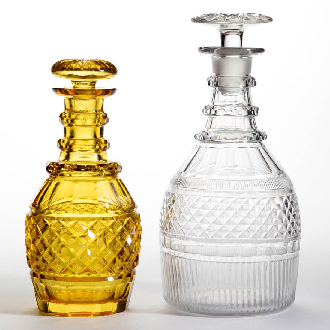 ASSORTED CUT GLASS DECANTERS, LOT OF TWO: ASSORTED CUT GLASS DECANTERS, LOT OF TWO, colorless and amber, each Prussian form with medial bands of cut-diamonds, amber with strawberry diamonds, each with cut-panelled shoulders and cut neck rings