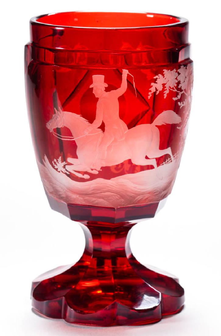 BOHEMIAN CUT AND ENGRAVED - RUBY-STAINED SPA BEAKER: BOHEMIAN CUT AND ENGRAVED - RUBY-STAINED SPA BEAKER, colorless, eight-sided body with a large central reserve depicting a gentleman with a top hat riding a sprinting horse that is jumping over a log, 