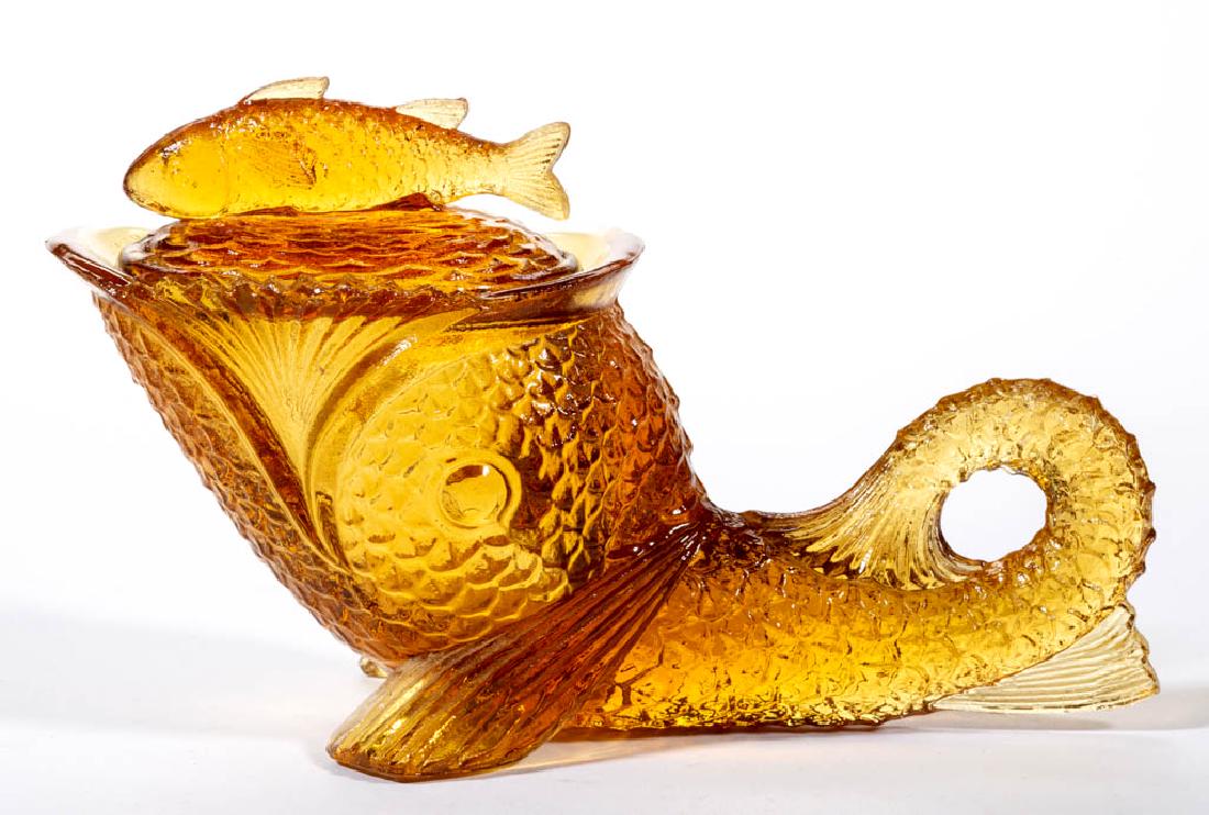 KEMPLE REPRODUCTION DOLPHIN COVERED DISH: KEMPLE REPRODUCTION DOLPHIN COVERED DISH, amber, with sawtooth rim. 20th century. 4 3/8" HOA, 7" LOA. Nearly undamaged with a single chip to the point of one sawtooth at the rim. Parallels Literature: