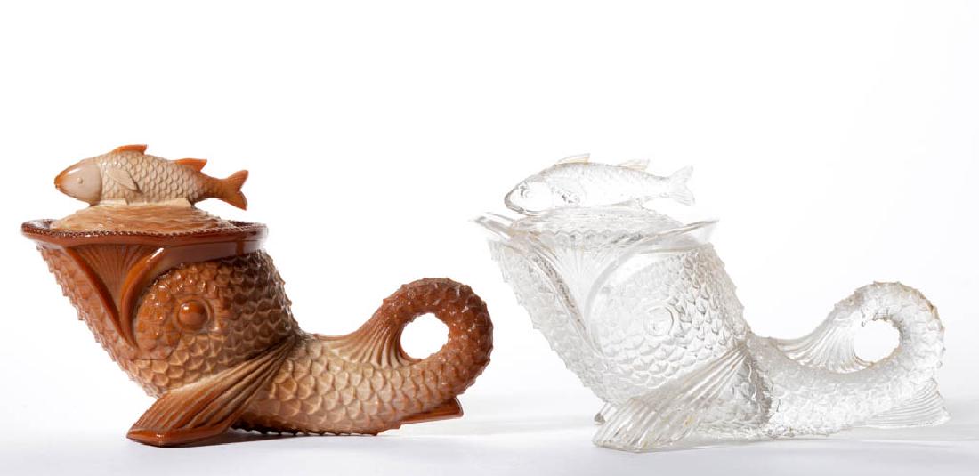 GREENTOWN DOLPHIN COVERED DISHES, LOT OF TWO: GREENTOWN DOLPHIN COVERED DISHES, LOT OF TWO, comprising a chocolate with a beaded rim, and a colorless with a sawtooth rim. Indiana Tumbler & Goblet Co. Circa 1902. 4 1/2" HOA, 7" LOA. Beaded rim und