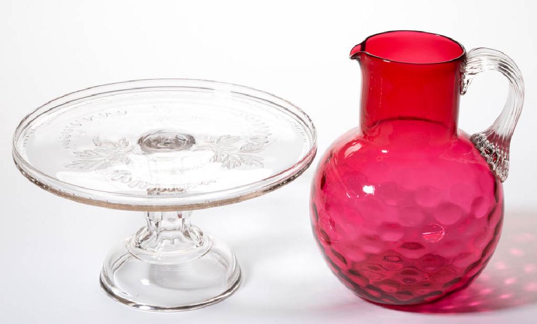 ASSORTED GLASS ARTICLES, LOT OF TWO: ASSORTED GLASS ARTICLES, LOT OF TWO, comprising a colorless Bleeding Heart cake stand and a cranberry Spot-Optic water pitcher with an applied colorless reeded handle. Various makers. Fourth quarter 1