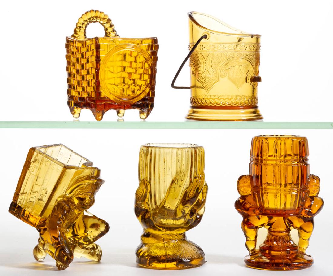 ASSORTED PRESSED NOVELTY TOOTHPICK HOLDERS, LOT OF FIVE: ASSORTED PRESSED NOVELTY TOOTHPICK HOLDERS, LOT OF FIVE, amber, including Peek-a-boo, Boy with Pack with Marble Shooter, and Coal Hod examples. Various makers. Late 19th/early 20th century. 3 3/8" to