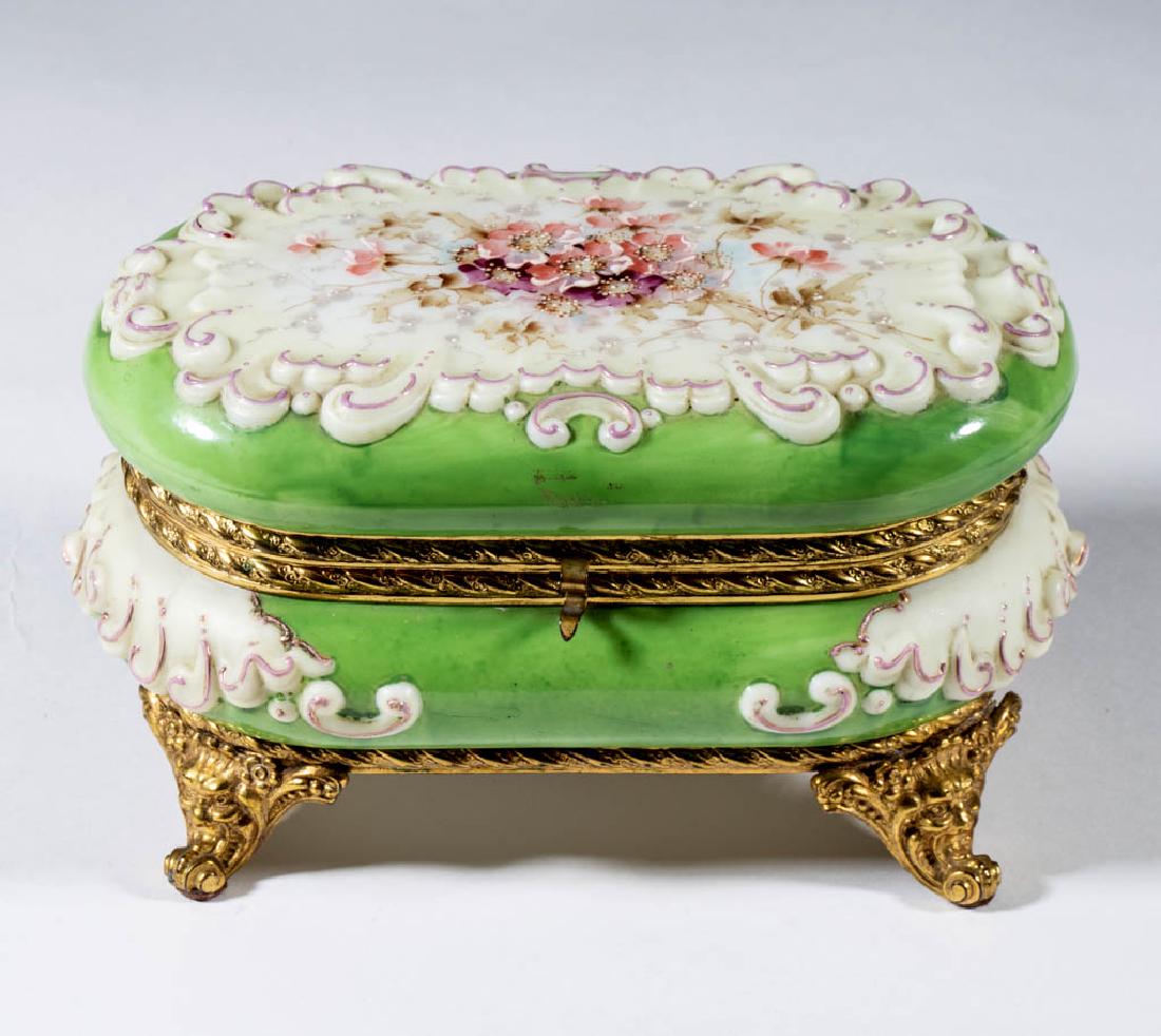 WAVE CREST ROCOCO OVAL FOOTED BOWL: WAVE CREST ROCOCO OVAL FOOTED BOWL, opal with polychrome-enamel decoration, green ground, floral decoration, original fancy brass mounts, lacking interior lining, signed. The C. F. Monroe Co. Late 19t