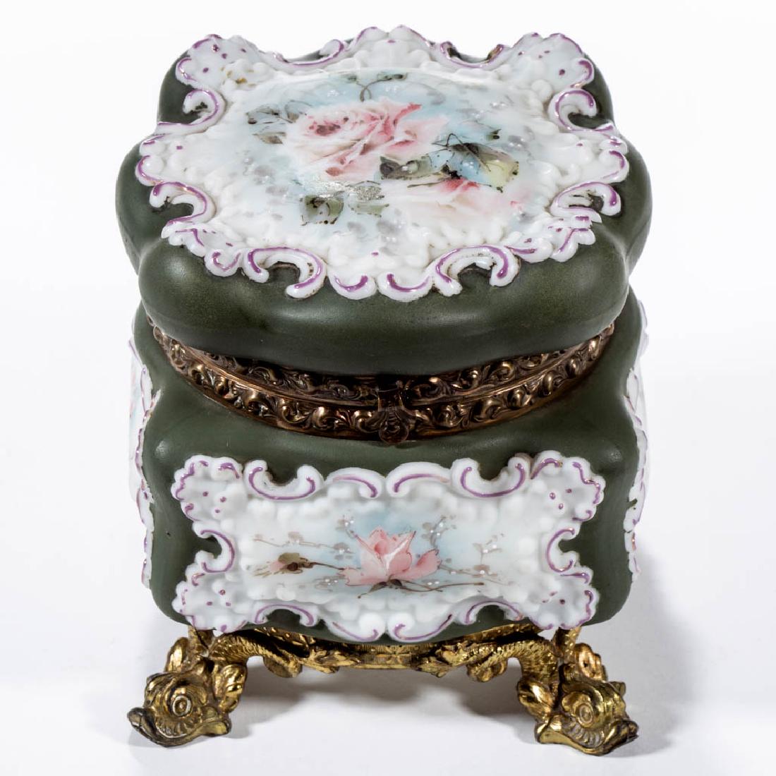 WAVE CREST ROCOCO SQUARE FOOTED BOWL: WAVE CREST ROCOCO SQUARE FOOTED BOWL, opal with polychrome-enamel decoration, deep green ground, floral decoration, original fancy brass mounts with dolphin feet, with interior lining, signed. The C. 