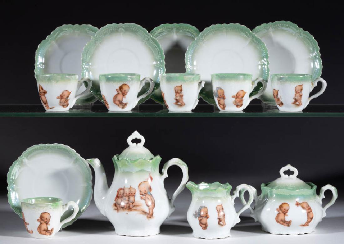 GERMAN PORCELAIN "KEWPIE" CHILDREN'S TOY 15-PIECE TEA: GERMAN PORCELAIN "KEWPIE" CHILDREN'S TOY 15-PIECE TEA SET, comprising a covered teapot, a creamer, a covered sugar, and six cups and saucers, each with polychrome Kewpie doll decals with light green l