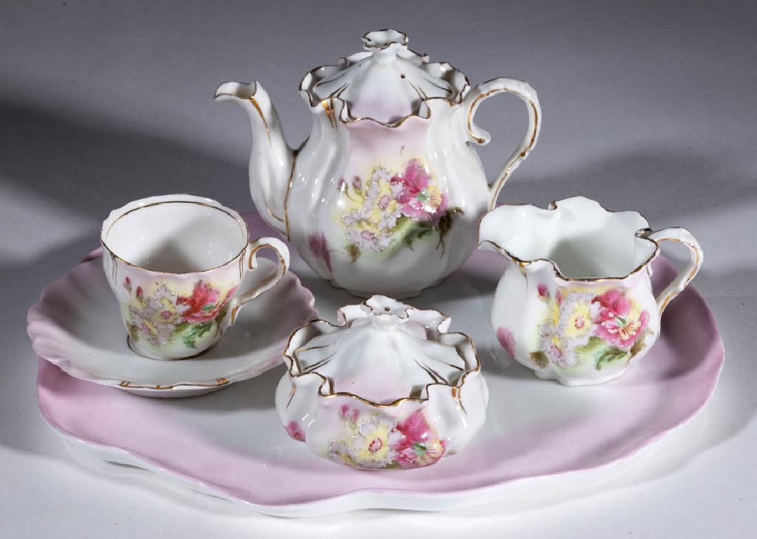 R.S. PRUSSIA PORCELAIN CHILDREN'S TOY SIX-PIECE TEA SET: R.S. PRUSSIA PORCELAIN CHILDREN'S TOY SIX-PIECE TEA SET, comprising a covered teapot, a covered squat sugar, a creamer, a cup and saucer, and a tray, each with polychrome hand-painted flowers on light