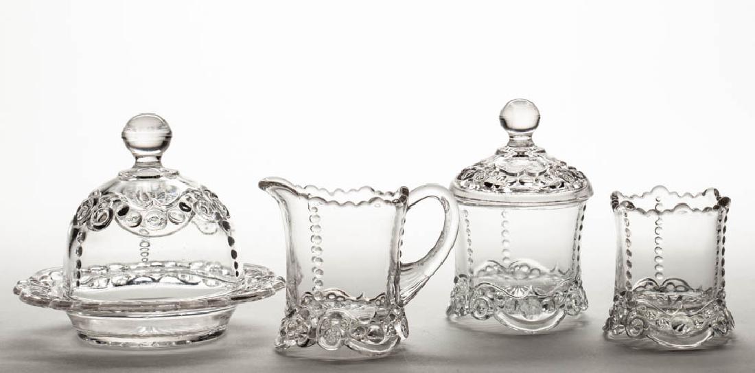 BEAD AND SCROLL CHILDREN'S TOY FOUR-PIECE TABLE SET: BEAD AND SCROLL CHILDREN'S TOY FOUR-PIECE TABLE SET, colorless, comprising a covered butter dish, covered sugar bowl, creamer, and spooner. Probably U.S. Glass Co. Circa 1899. 2 1/2" to 4" HOA. Undama