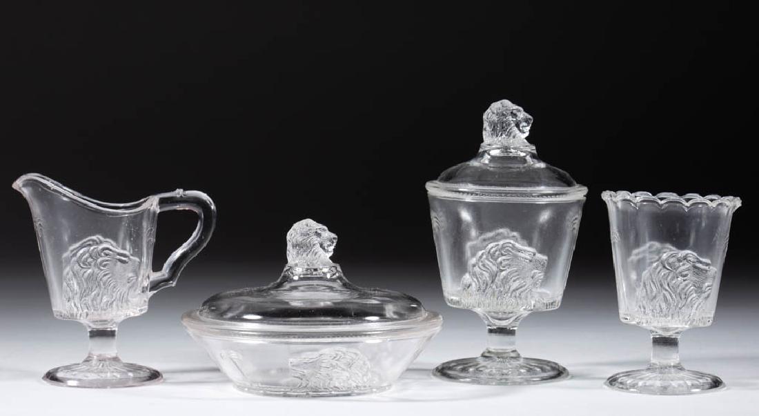 LION CHILDREN'S TOY FOUR-PIECE TABLE SET: LION CHILDREN'S TOY FOUR-PIECE TABLE SET, colorless, comprising a covered butter dish, covered sugar bowl, creamer, and spooner. Gillinder & Sons. Circa 1876. 2 3/4" to 4 3/8" HOA. Creamer with two mi