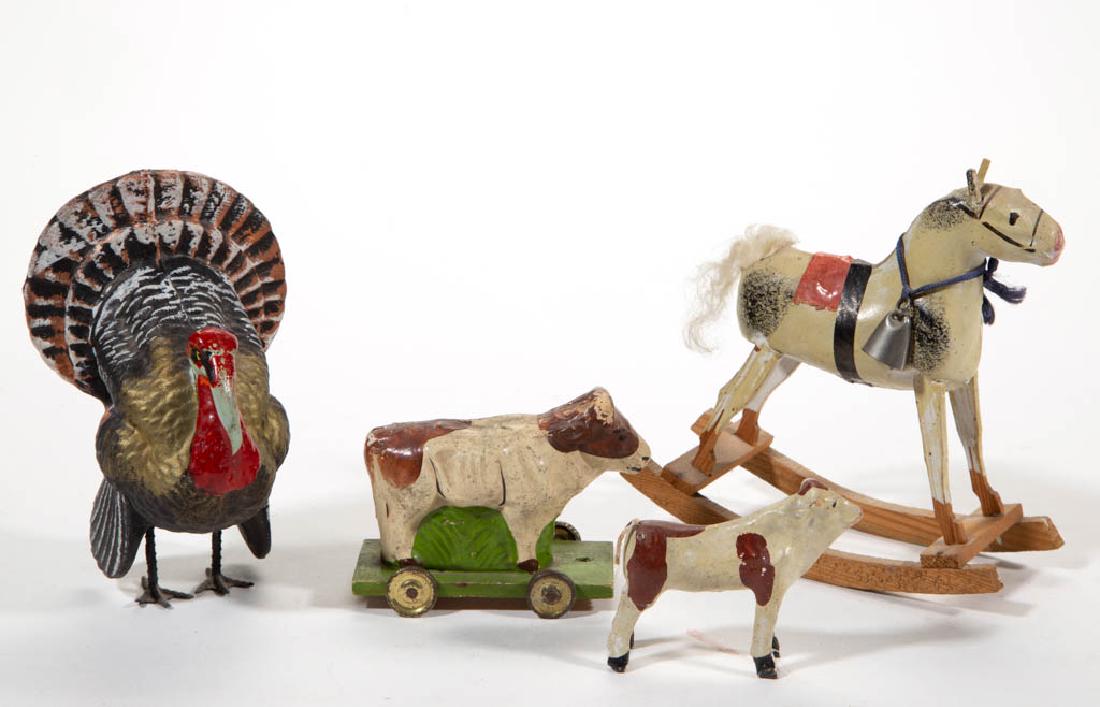 GERMAN COMPOSITION / PAPIER-MACHE ANIMALS, LOT OF FOUR: GERMAN COMPOSITION / PAPIER-MACHE ANIMALS, LOT OF FOUR, comprising a tom turkey candy container, rocking horse, cow pull toy, and standing cow, two marked "Germany". Late 19th/early 20th century. 2 3/