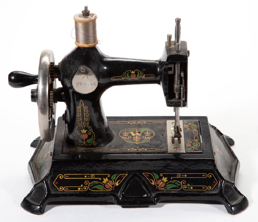GERMAN CAST-IRON CHILD'S SEWING MACHINE: GERMAN CAST-IRON CHILD'S SEWING MACHINE, with original stenciled decorations, No. 9042. Late 19th/first quarter 20th century. 7" HOA, 9 3/4" x 6 3/4". Excellent working condition. Provenance: Property