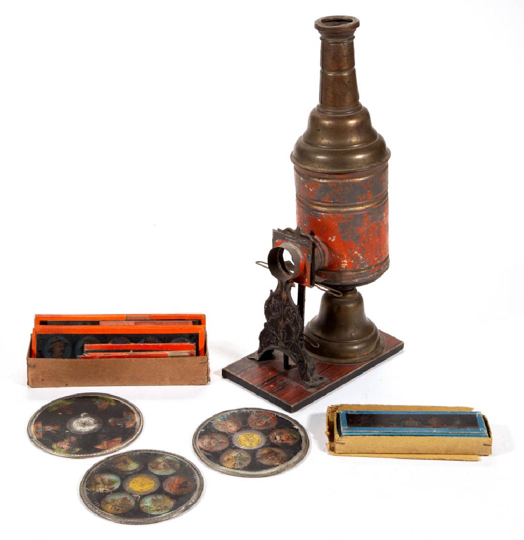 GERMAN MAGIC LANTERN WITH ACCESSORIES: GERMAN MAGIC LANTERN WITH ACCESSORIES, unusual form, painted-tin applied to a paint-decorated wooden board, retains three original round slides and an uncounted number of other period rectangular slid