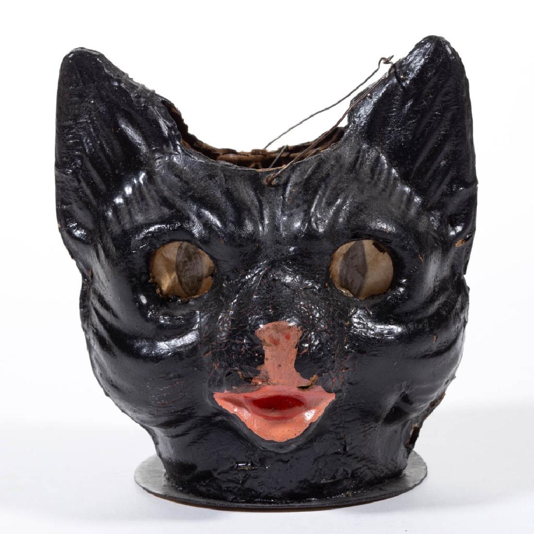 HALLOWEEN COMPOSITION / CARDBOARD BLACK CAT: HALLOWEEN COMPOSITION / CARDBOARD BLACK CAT JACK-O-LANTERN, painted finish, having eye paper inserts, wire hanging handle. Printed "Germany" mark to base. First half 20th century or later. 4 3/4" HOA.
