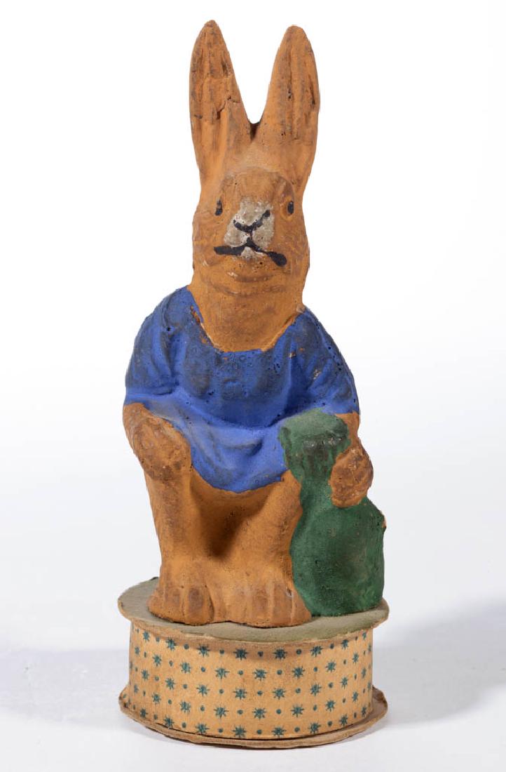 GERMAN COMPOSITION / PAPIER-MACHE RABBIT CANDY: GERMAN COMPOSITION / PAPIER-MACHE RABBIT CANDY CONTAINER, a sitting anthropomorphized rabbit having polychrome-painted finish mounted to round box base. Printed "Germany" mark to base. First quarter 2