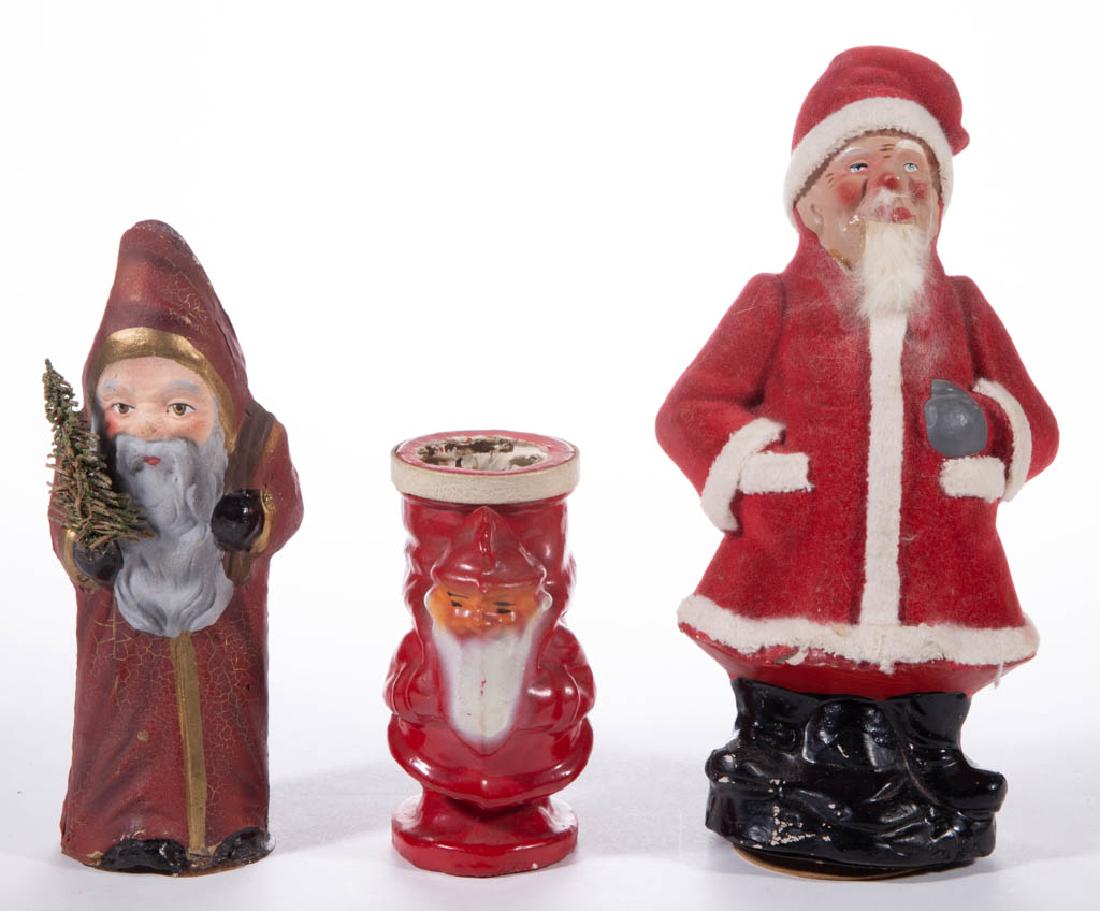 GERMAN COMPOSITION / PAPIER-MACHE SANTA CLAUS CANDY: GERMAN COMPOSITION / PAPIER-MACHE SANTA CLAUS CANDY CONTAINERS, LOT OF THREE, including a Belsnickle example with faux tree branch in one hand. Unmarked. First half 20th century. 4 1/2" to 8 1/2" HOA.