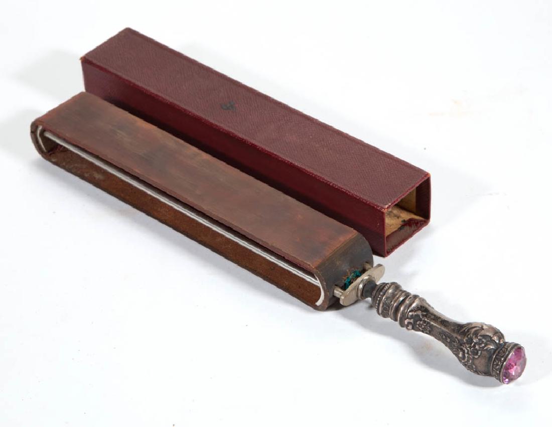 FOSTER & BAILEY, PROVIDENCE, RHODE ISLAND RAZOR STROP: FOSTER & BAILEY, PROVIDENCE, RHODE ISLAND RAZOR STROP, sterling silver impressed "PAT'D Sterling F&B", F&B are encompassed inside a flag, amethyst pommel, with a sheath. Late 19th century. 12 1/2" LOA