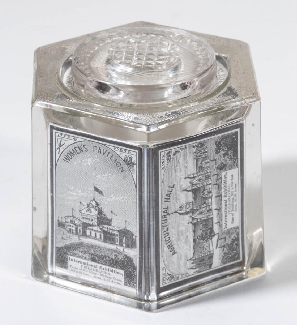 1876 PHILADELPHIA CENTENNIAL EXPOSITION PATENTED GLASS: 1876 PHILADELPHIA CENTENNIAL EXPOSITION PATENTED GLASS MATCH SAFE / INK WELL, colorless, hexagonal form with a printed-paper view of a different building mounted to the interior of each side, another 