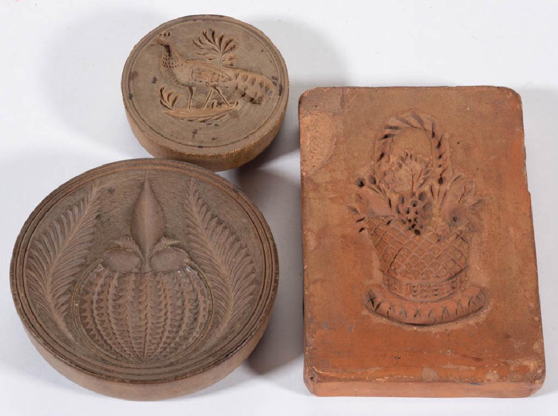 PENNSYLVANIA EARTHENWARE / REDWARE RECTANGULAR BUTTER: PENNSYLVANIA EARTHENWARE / REDWARE RECTANGULAR BUTTER PRINT, depicting a basket of flowers and fruit, smooth back. Together with two carved treen circular butter prints, one depicting a peacock, each