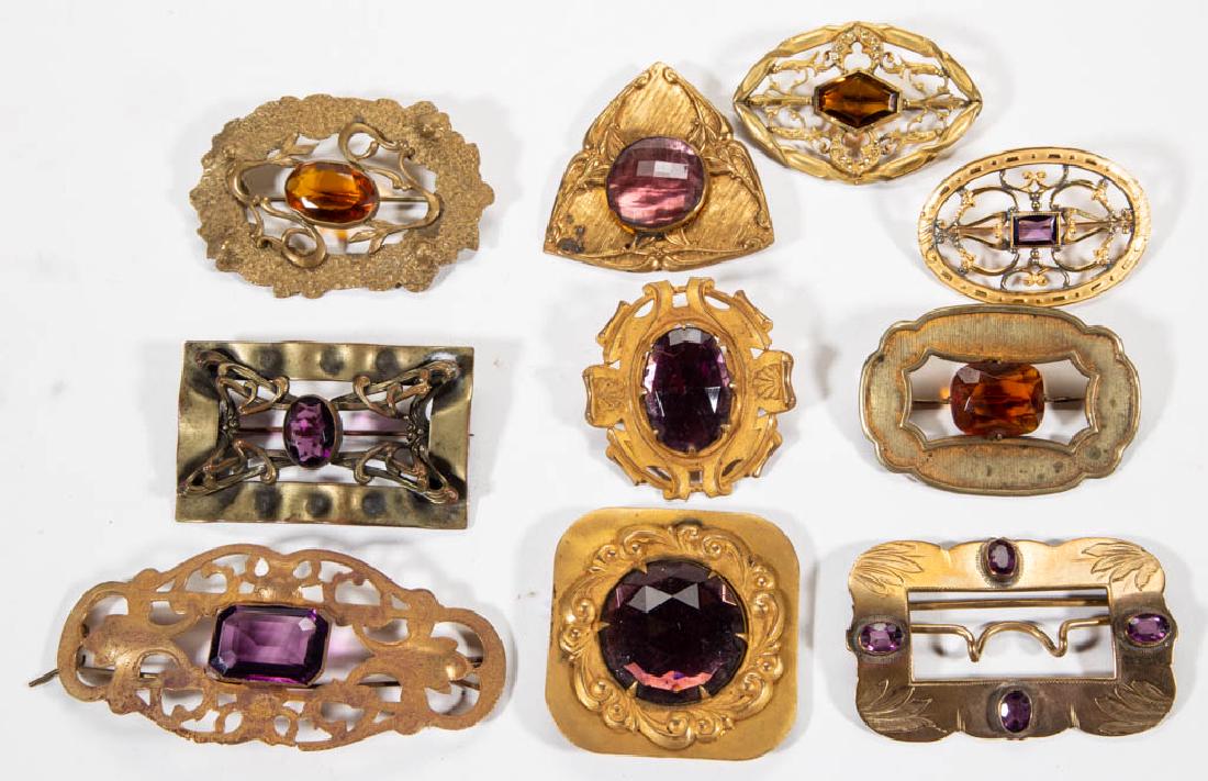 ASSORTED COLORED STONE EMBELLISHED BROOCHES / SCARF: ASSORTED COLORED STONE EMBELLISHED BROOCHES / SCARF CLIPS, LOT OF TEN, brass/gold finishes, various patterns of ornamentation with a medial stone in amethyst, citrine, or smoky topaz, comprising nine 