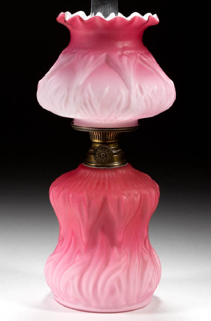 EMBOSSED STYLIZED TULIP MINIATURE LAMP: EMBOSSED STYLIZED TULIP MINIATURE LAMP, cased dark to light rose with satin finish, cylinder-form font with pinched waist, matching pattern umbrella-form shade with crimped rim, brass collar. Fitted w