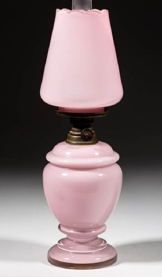 CASED GLASS MINIATURE LAMP: CASED GLASS MINIATURE LAMP, cased soft pink, pyriform font with pedestal foot and ringed shoulder, matching pattern conical-form shade with scalloped rim, period collar. Fitted with a Spar Brenner bur