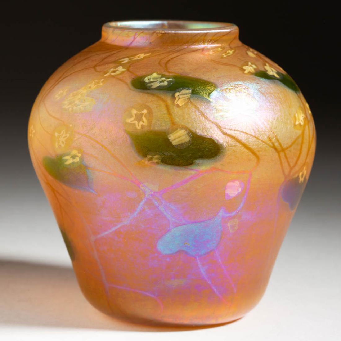 TIFFANY FAVRILE MILLEFIORI IRIDESCENT ART GLASS VASE: TIFFANY FAVRILE MILLEFIORI IRIDESCENT ART GLASS VASE, golden iridescent with green decoration, ovoid form with scattered opal floral millefiori canes above a leaf and vine design, factory-polished bas