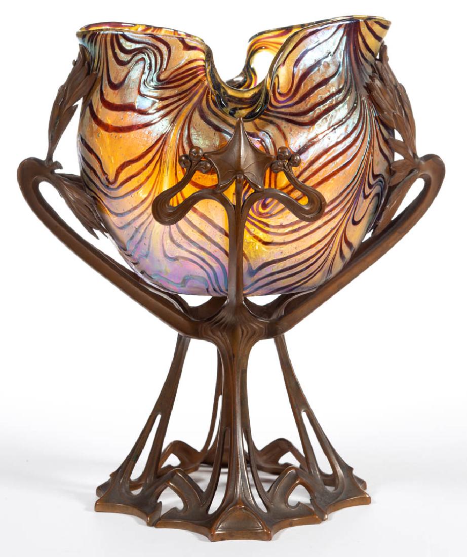 KRALIK AMETHYST ON GOLD IRIDESCENT ART GLASS: KRALIK AMETHYST ON GOLD IRIDESCENT ART GLASS PEDESTALLED BOWL, golden iridescent with applied amethyst decoration, ovoid form with a tooled rim, fitted into a metal stand with a foliate motif and havi