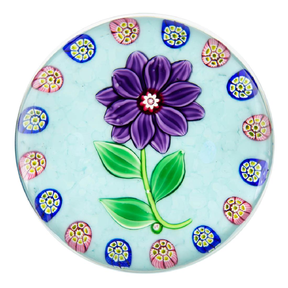PAUL YSART LAMPWORK AND MILLEFIORI STUDIO ART GLASS: PAUL YSART LAMPWORK AND MILLEFIORI STUDIO ART GLASS PAPERWEIGHT, colorless, central purple flower with six petal in the foreground and six in the background, thin green stem with three leaves, outer b