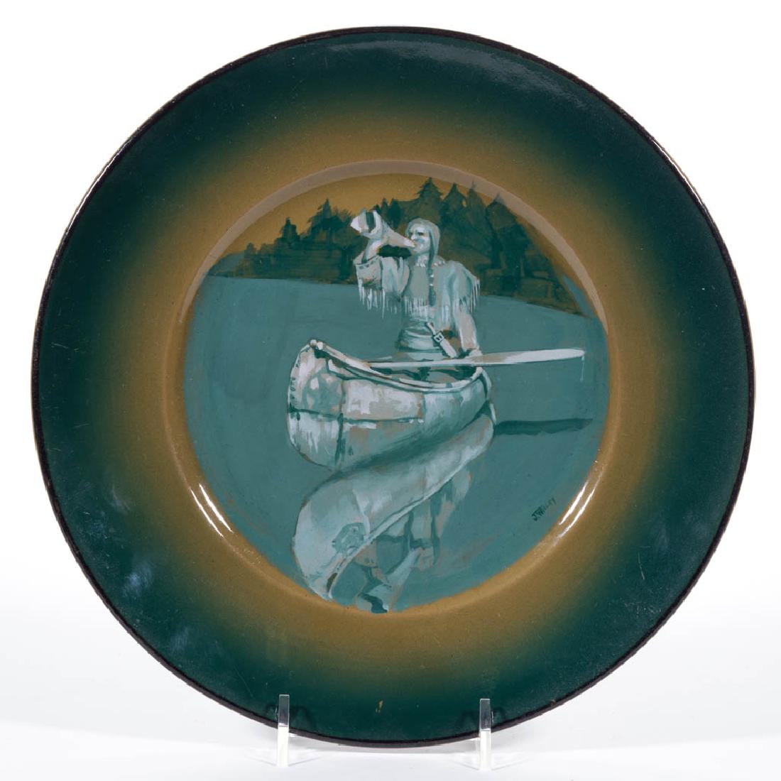 AMERICAN BUFFALO POTTERY DELDARE NATIVE AMERICAN: AMERICAN BUFFALO POTTERY DELDARE NATIVE AMERICAN CERAMIC PLATE, with central teal hand-painted image of Native American in canoe blowing a moose call and signed "J. Wigley" in lower right corner. Prin