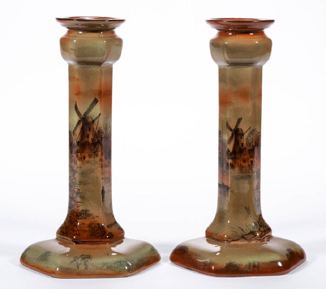 AMERICAN BUFFALO POTTERY ABINO WARE CERAMIC CANDLESTICK: AMERICAN BUFFALO POTTERY ABINO WARE CERAMIC CANDLESTICK PAIR, comprising two matching hexagonal-shaped examples with rust-colored hand-painted windmill and boat scenes and both signed "W.E. Simpson". 