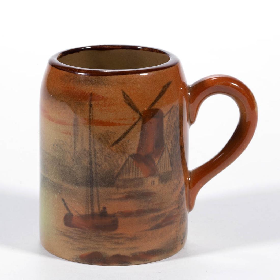 AMERICAN BUFFALO POTTERY ABINO WARE CERAMIC MUG: AMERICAN BUFFALO POTTERY ABINO WARE CERAMIC MUG, with rust-colored hand-painted windmill and boat scene, signed "C. HARRIS" below handle. Hand-brushed mark "ABINO WARE / BUFFALO / POTTERY / 1913" and