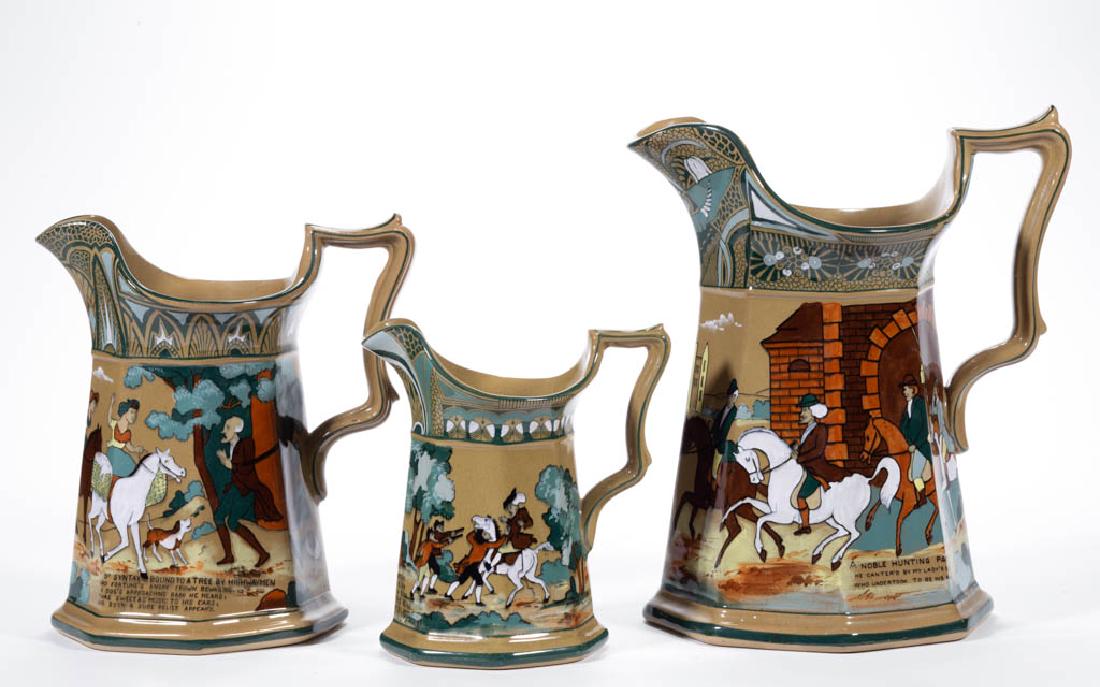 AMERICAN BUFFALO POTTERY EMERALD DELDARE DR. SYNTAX: AMERICAN BUFFALO POTTERY EMERALD DELDARE DR. SYNTAX CERAMIC PITCHERS, LOT OF THREE, each having an octagonal, panelled body with Art Nouveau-style border, having scenes including "A Noble Hunting Part