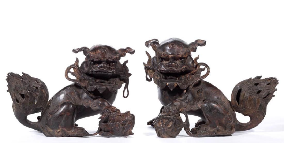 CHINESE CAST-BRONZE PAIR OF GUARDIAN LIONS / FOO DOGS: CHINESE CAST-BRONZE PAIR OF GUARDIAN LIONS / FOO DOGS, both with open mouths, the female (yin) is holding down a puppy, and the male (yang) is holding down a ball. Probably 20th century. 7" and 7 3/4"