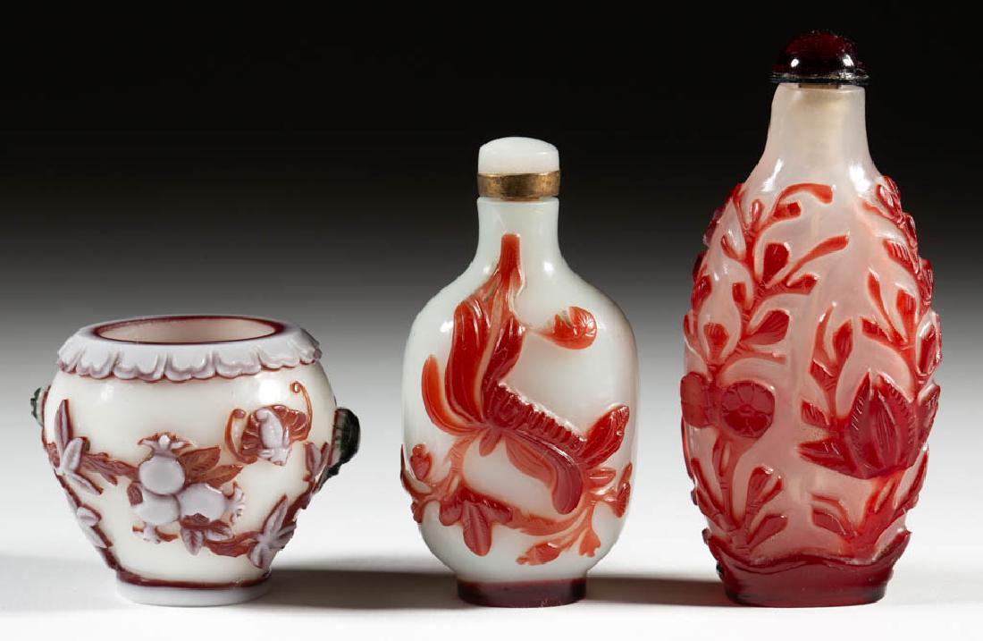 CHINESE CARVED PEKING CAMEO GLASS SNUFF BOTTLES, LOT OF: CHINESE CARVED PEKING CAMEO GLASS SNUFF BOTTLES, LOT OF TWO, each having bas-relief carving design and topped by a cap with attached snuff spoon, taller example with cloudy colorless ground having fol