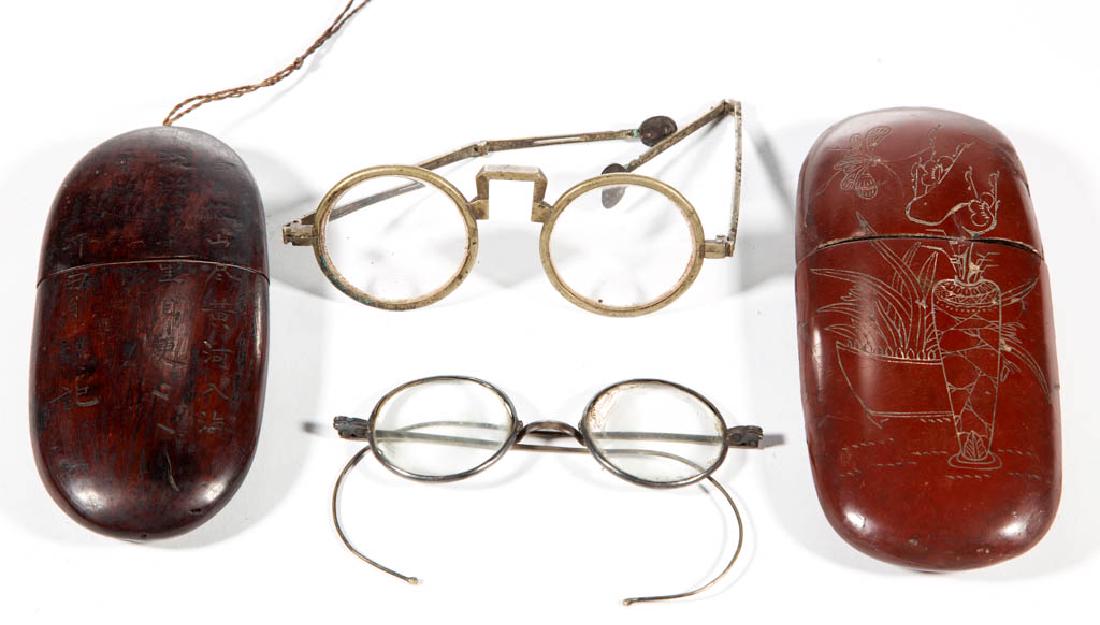 CHINESE EYEGLASSES AND CASES, LOT OF TWO: CHINESE EYEGLASSES AND CASES, LOT OF TWO, comprising a red lacquered case with floral design and a poem on the other side having brass-rimmed glasses with curved temples, and a mahogany case with carv