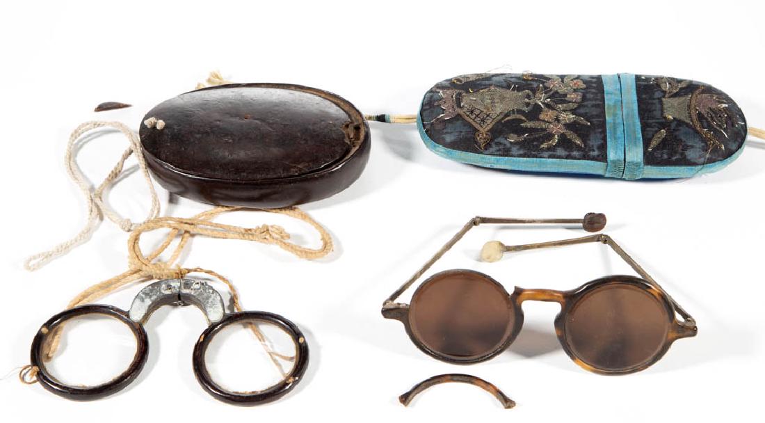 CHINESE EYEGLASSES AND CASES, LOT OF TWO: CHINESE EYEGLASSES AND CASES, LOT OF TWO, comprising an embroidered case with shell-like glasses having smoked lenses, and a lacquered mahogany case with folding glasses. Second half 19th/early 20th c