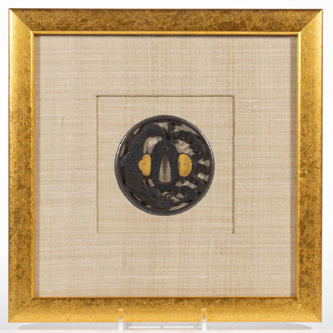 JAPANESE EDO PERIOD KINAI SCHOOL IRON TSUBA: JAPANESE EDO PERIOD KINAI SCHOOL IRON TSUBA, having openwork design featuring a fish figure and waves, gilt-plugged kogai hitsu-ana and kozuka hitsu-ana. Signed to center. Housed under glass in a mode