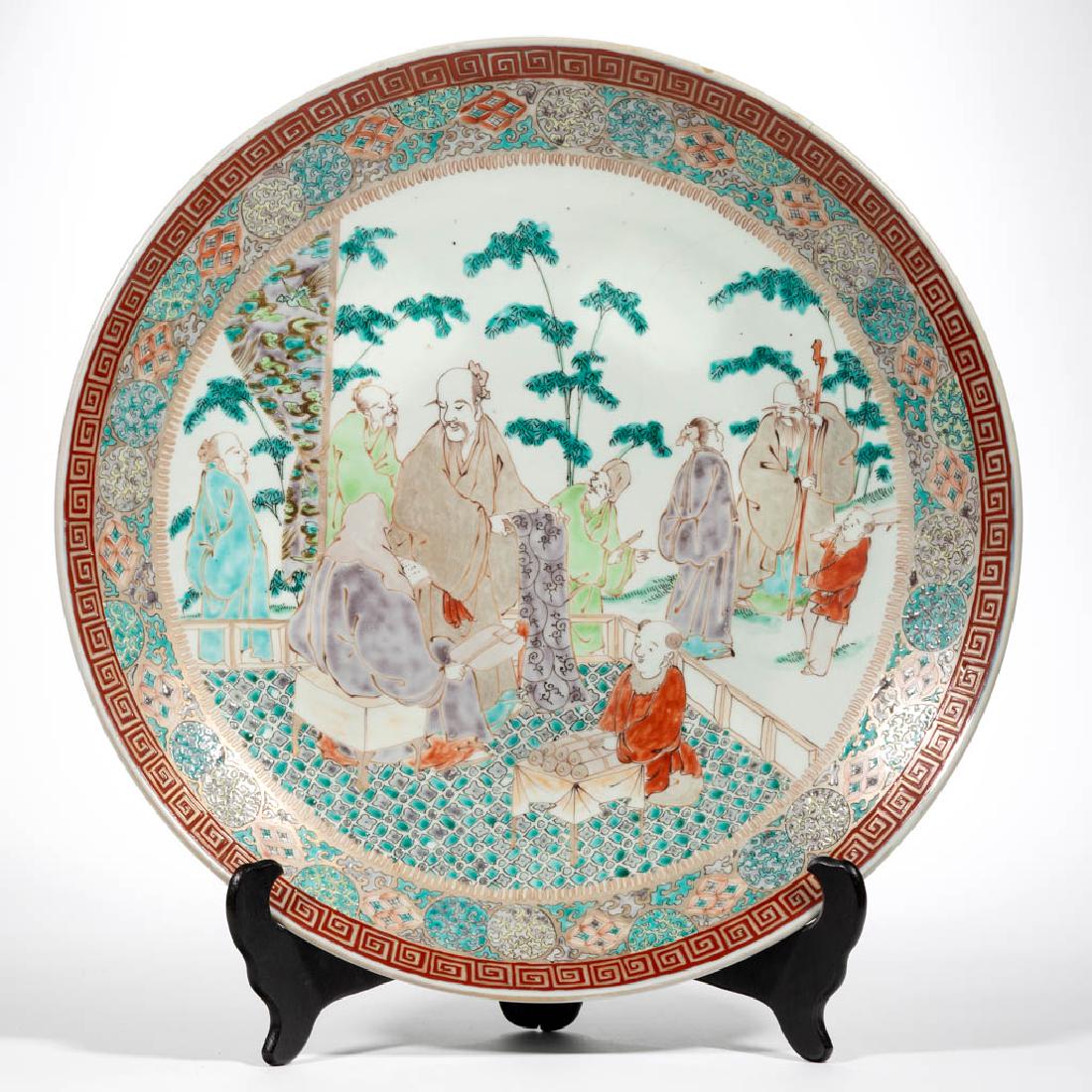 CHINESE EXPORT PORCELAIN CHARGER: CHINESE EXPORT PORCELAIN CHARGER, having polychrome enamel decorated images of seven scholars and two children with a central figure sitting having head covered holding a fan and book with a standing