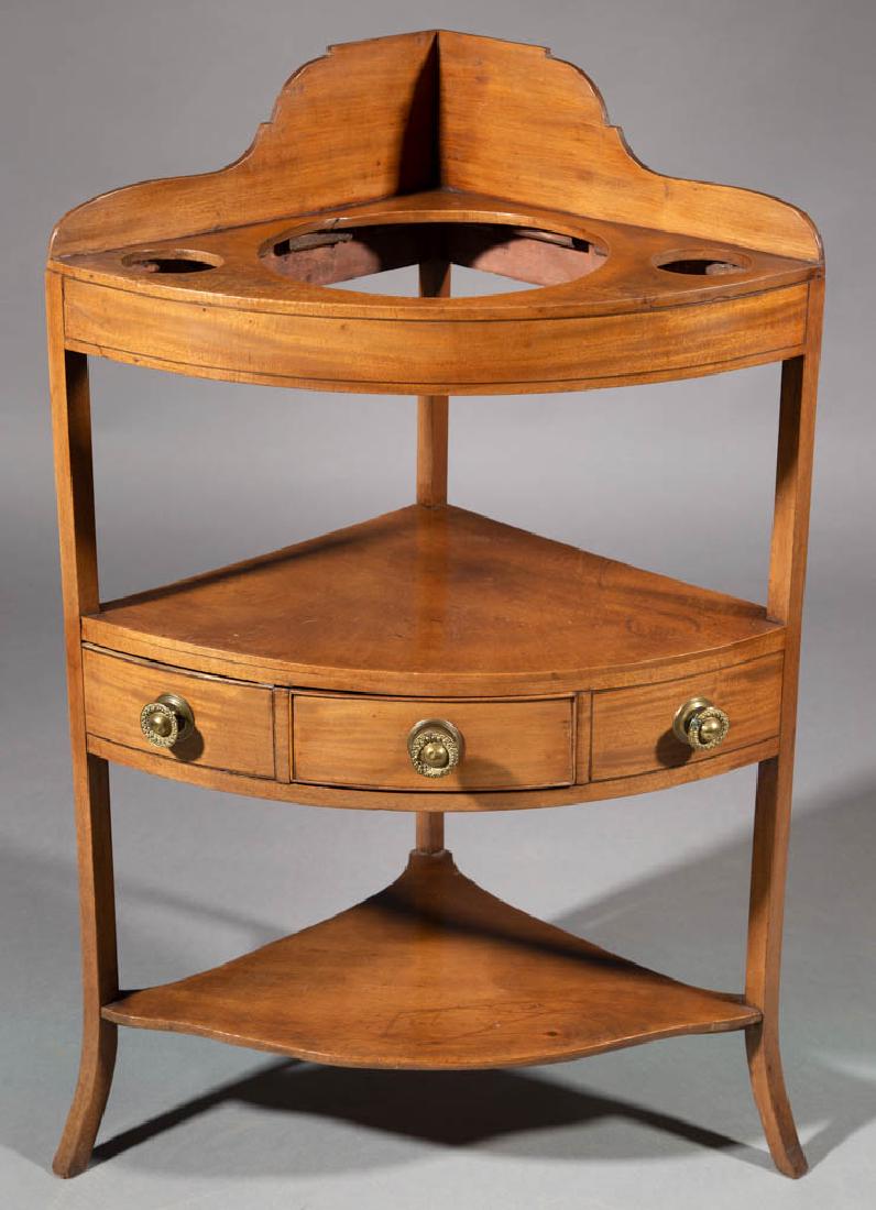 GEORGIAN MAHOGANY CORNER WASHSTAND: GEORGIAN MAHOGANY CORNER WASHSTAND, triangular top fitted with shaped gallery with basin and two other cut outs, raised on legs with flared feet, fitted with medial shelf above single drawer flanked b