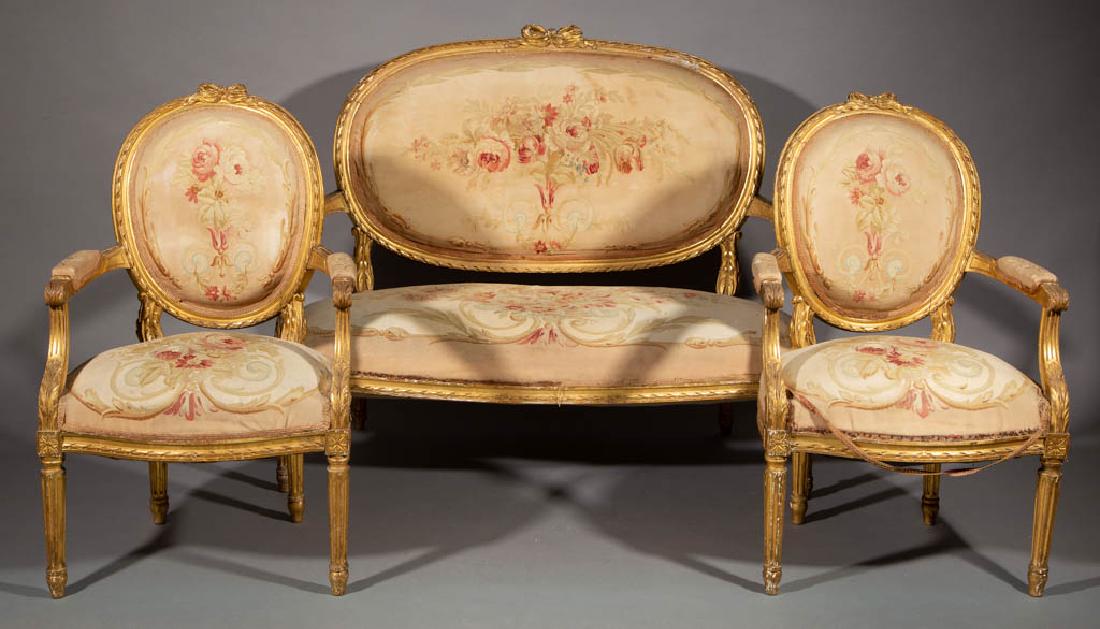 FRENCH LOUIS XV-STYLE CARVED GILTWOOD SALON / PARLOR: FRENCH LOUIS XV-STYLE CARVED GILTWOOD SALON / PARLOR SUITE, comprising two fauteuil armchairs and a settee, each with floral tapestry upholstery, likely original. Late 19th/early 20th century. 38" HOA