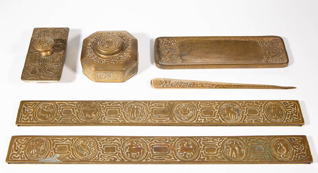 TIFFANY STUDIOS ZODIAC BRONZE SIX-PIECE PARTIAL DESK: TIFFANY STUDIOS ZODIAC BRONZE SIX-PIECE PARTIAL DESK SET, comprising two blotter ends, a small inkwell lacking glass insert, a letter opener with later design, a pen tray, and a rocker blotter, each s